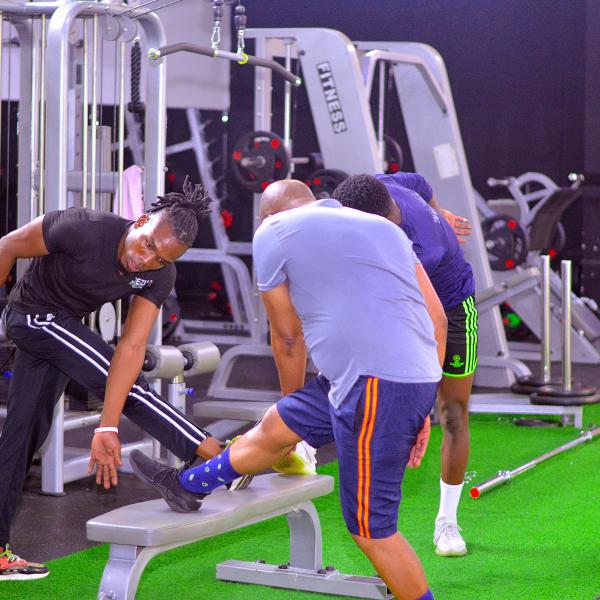 A Zoezi coach guiding members through a strength exercise on the gym floor